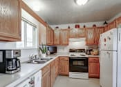 Thumbnail 25 of 27 - A kitchen with wooden cabinets and white appliances.