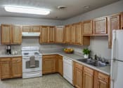 Thumbnail 27 of 29 - A kitchen with wooden cabinets and a white stove top oven.