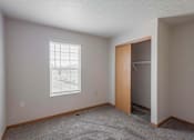 Thumbnail 44 of 59 - A room with a carpeted floor, a window with blinds, and a wooden door.