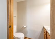 Thumbnail 33 of 59 - A white toilet is in a small bathroom with a wooden door.