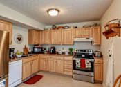 Thumbnail 26 of 27 - A kitchen with wooden cabinets and stainless steel appliances.
