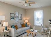 Thumbnail 41 of 42 - A living room with a beige couch, a wooden coffee table, and a ceiling fan.