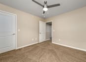 Thumbnail 14 of 16 - A room with a ceiling fan and carpeted floor.