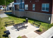Thumbnail 7 of 36 - a patio with three benches and a trash can in front of a brick building