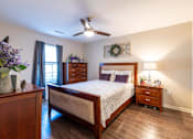 Thumbnail 16 of 55 - A bedroom with a bed, nightstand, and a window with curtains.