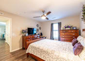 Thumbnail 17 of 55 - A bedroom with a bed, dresser, and ceiling fan.