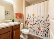 Thumbnail 21 of 55 - A bathroom with a floral shower curtain and a white toilet.