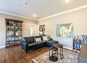 Thumbnail 29 of 55 - A living room with a black leather couch and a wooden floor.