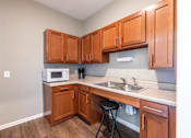 Thumbnail 31 of 55 - A kitchen with wooden cabinets and a white microwave.