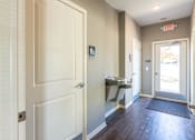 Thumbnail 33 of 55 - A hallway with a white door and a red exit sign above it.