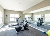 Thumbnail 34 of 55 - A spacious home gym with a treadmill, elliptical machines, and a weight bench.