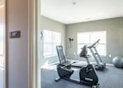 Thumbnail 36 of 55 - A gym with a treadmill and exercise bike.