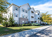 Thumbnail 45 of 55 - A white apartment building with a green lawn in front.