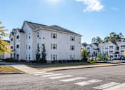 Thumbnail 46 of 55 - A white building with a grey roof is in the background of a street with a crosswalk.