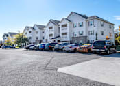 Thumbnail 47 of 55 - A parking lot with cars and apartment buildings in the background.