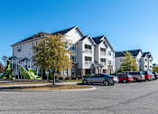Thumbnail 48 of 55 - Apartment complex with a playground and cars parked in front.