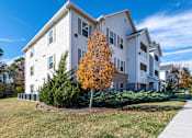 Thumbnail 51 of 55 - A white two-story apartment building with a yellow tree in front.