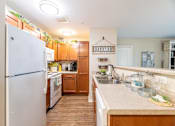 Thumbnail 12 of 55 - A kitchen with a white refrigerator and wooden cabinets.