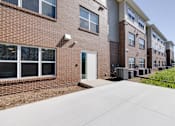 Thumbnail 1 of 27 - a walkway leading to a brick building with a white door