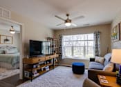 Thumbnail 17 of 27 - a living room with a couch and a tv in front of a window