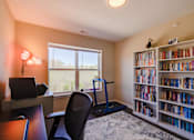 Thumbnail 13 of 27 - a home office with a bookshelf and treadmill