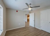 Thumbnail 10 of 32 - A room with a ceiling fan and wooden flooring.