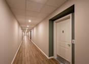 Thumbnail 16 of 32 - A long hallway with a white door at the end.