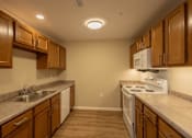 Thumbnail 2 of 32 - A kitchen with brown cabinets and a white stove top oven.