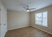 Thumbnail 8 of 32 - A room with a ceiling fan and a window overlooking a parking lot.