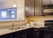 Thumbnail 2 of 21 - a kitchen with black appliances and granite counter tops