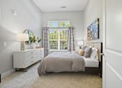 Thumbnail 5 of 20 - A bedroom with a bed, nightstand, and window.