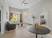 Thumbnail 3 of 20 - A living room with a grey couch, a black table, and a ceiling fan.
