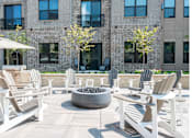 Thumbnail 13 of 19 - A patio with white chairs and a fire pit.