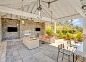 Thumbnail 25 of 28 - a covered patio with a stone fireplace and furniture