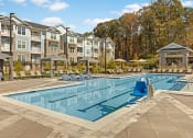 Thumbnail 3 of 28 - a swimming pool with chairs around it in front of an apartment building