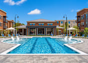 Thumbnail 12 of 23 - A large swimming pool in front of a building with a glass facade.