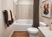 Thumbnail 10 of 14 - A bathroom with a white tub, toilet, and sink.
