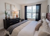 Thumbnail 5 of 14 - A bedroom with a large bed and a window with black curtains.