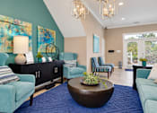 Thumbnail 20 of 22 - Leasing office lounge with upholstered seating, a round coffee table and coastal artwork at Canterbury Apartments in Myrtle Beach, SC.