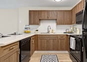 Thumbnail 2 of 22 - Kitchen with wood cabinets, black appliances and a breakfast bar at Canterbury Apartments in Myrtle Beach, SC.