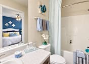 Thumbnail 7 of 22 - Bathroom with a vanity, white tub and shower combination, and a mirror reflecting the bedroom at Canterbury Apartments.
