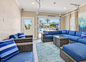 Thumbnail 13 of 22 - Resident lounge with blue cushioned seating, wicker tables and counter seating at Canterbury Apartments in Myrtle Beach, SC.