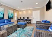 Thumbnail 14 of 22 - Resident lounge with blue sectional seating and a glass garage door overlooking the pool at Canterbury Apartments in Myrtle Beach, SC.