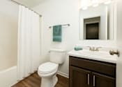 Thumbnail 5 of 18 - A white toilet sits in a bathroom next to a sink.