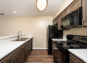 Thumbnail 2 of 18 - a kitchen with black appliances and white counter tops and wood floors