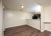 Thumbnail 9 of 18 - an empty living room with wood flooring and a kitchen