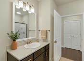 Thumbnail 4 of 15 - A bathroom with a sink, mirror, and a door.