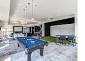 Thumbnail 7 of 19 - A pool table is in the middle of a room with a green rug and a dining table.
