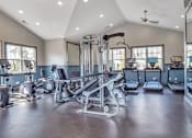 Thumbnail 11 of 34 - A spacious gym with various exercise equipment and a ceiling fan.