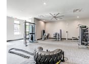 Thumbnail 15 of 19 - A gym with a variety of equipment including a tire flipping machine.